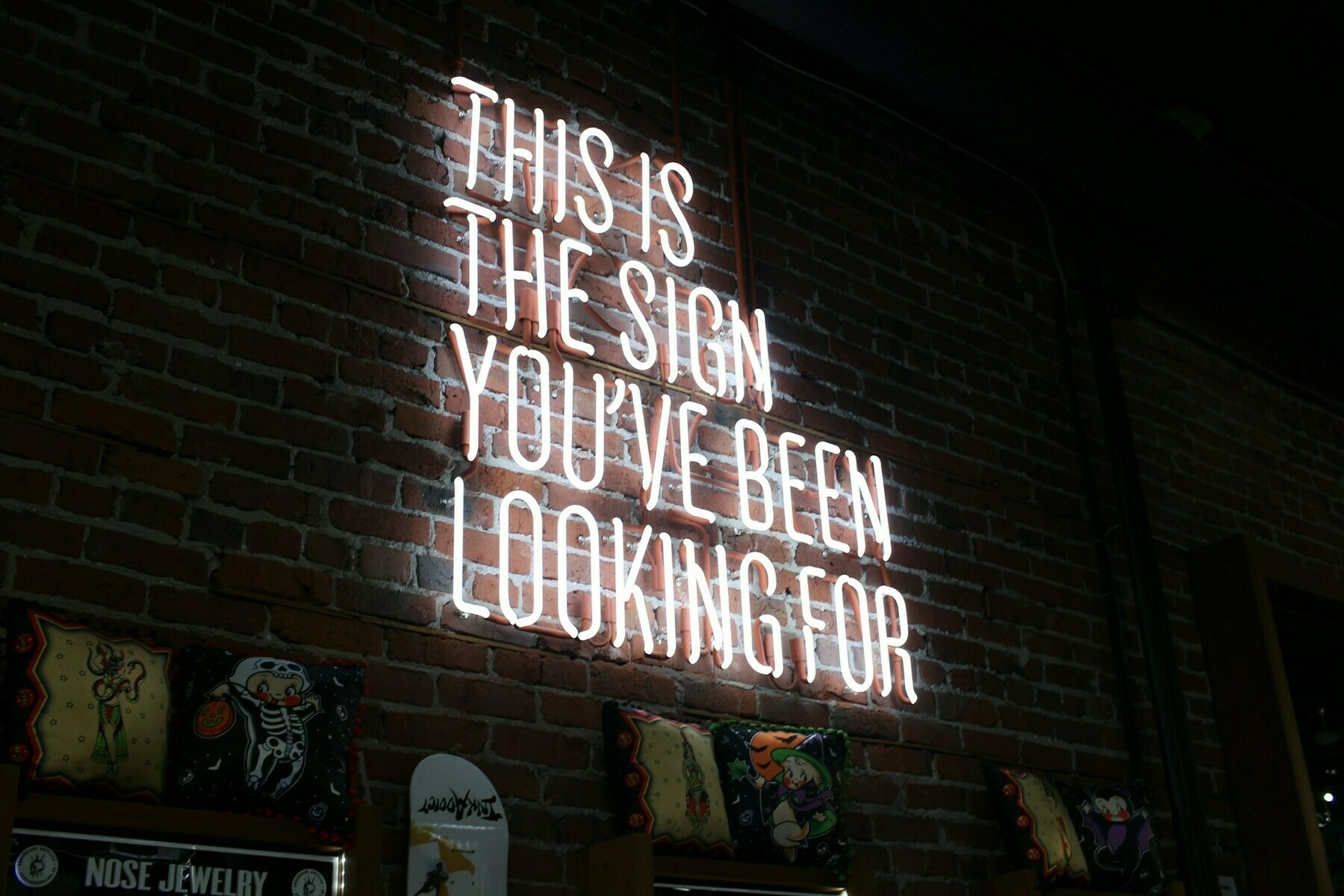 Auto-generated description: A neon sign on a brick wall displays the text THIS IS THE SIGN YOU'VE BEEN LOOKING FOR.