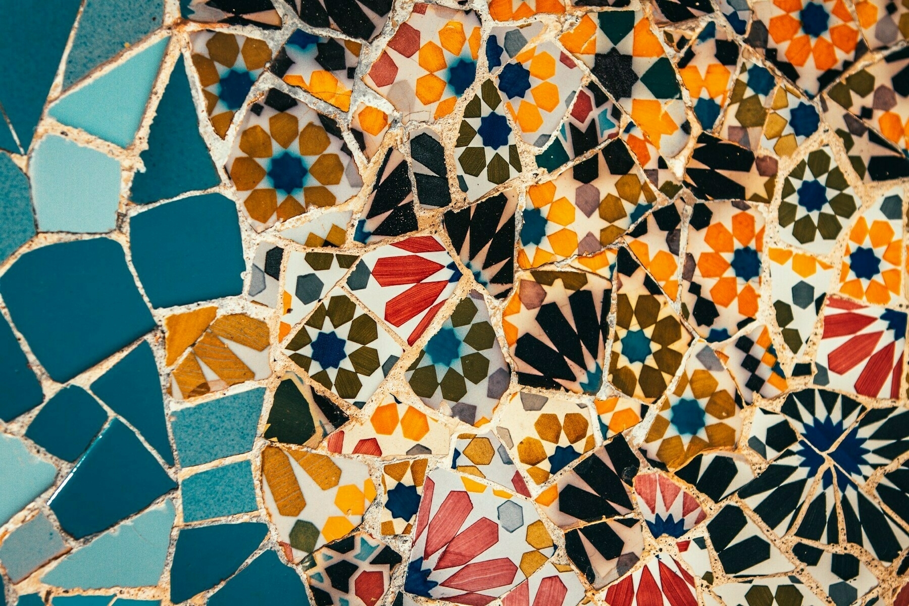 Auto-generated description: A colorful mosaic pattern featuring various geometric shapes and vibrant floral designs.